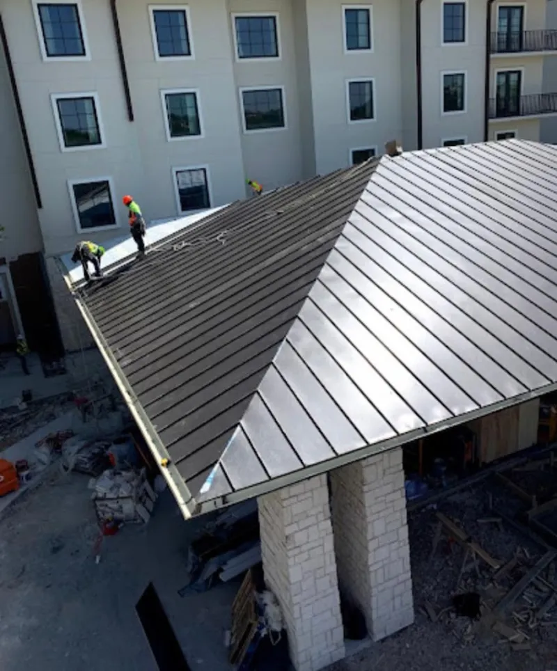 Crew installing standing seam metal roof panels on a commercial project in Cranston